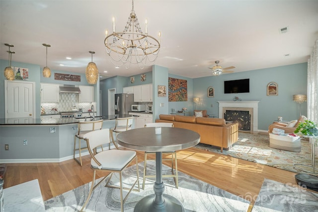 dining room with ceiling fan with notable chandelier and light hardwood / wood-style floors