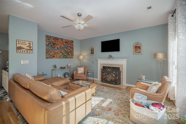 living room featuring light hardwood / wood-style floors, ceiling fan, and a premium fireplace