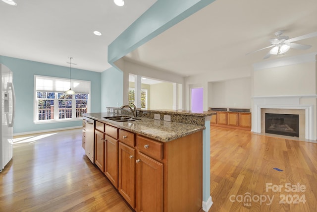 kitchen featuring light wood-type flooring, plenty of natural light, hanging light fixtures, and sink