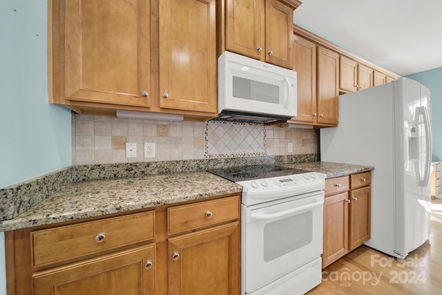 kitchen with backsplash, light stone countertops, light hardwood / wood-style flooring, and white appliances