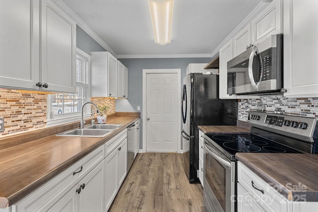 kitchen with white cabinets, sink, stainless steel appliances, and wooden counters