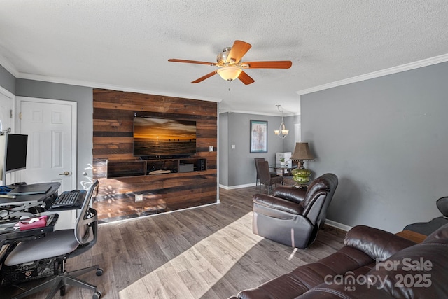 living room featuring wood walls, crown molding, ceiling fan with notable chandelier, and a textured ceiling