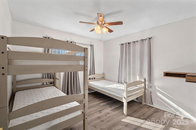 bedroom featuring hardwood / wood-style floors, ceiling fan, and a textured ceiling