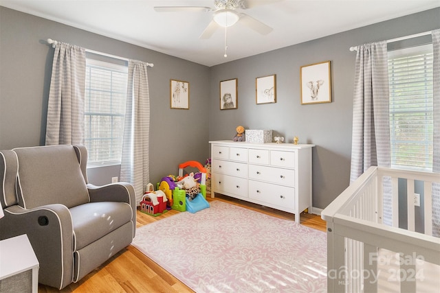 bedroom featuring a crib, hardwood / wood-style flooring, and ceiling fan