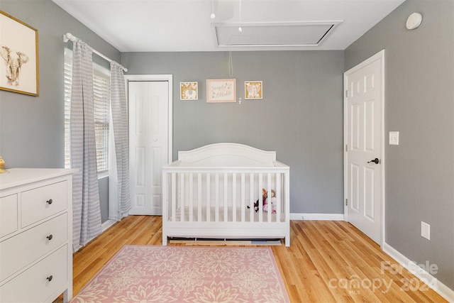 bedroom featuring a closet, a crib, and light hardwood / wood-style flooring