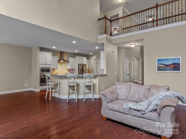 living room featuring a towering ceiling and dark hardwood / wood-style floors