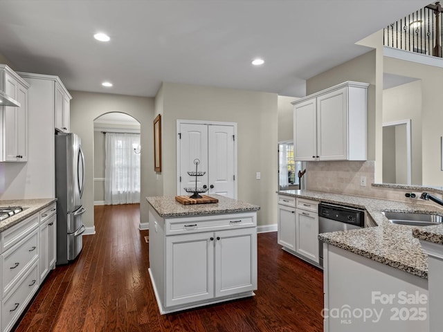 kitchen featuring appliances with stainless steel finishes, dark wood-type flooring, a kitchen island, white cabinets, and sink