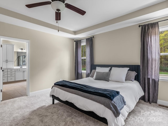 bedroom featuring ensuite bath, light carpet, and ceiling fan