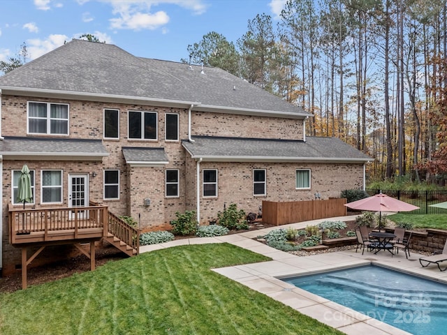 rear view of property with a yard, a swimming pool side deck, and a patio area