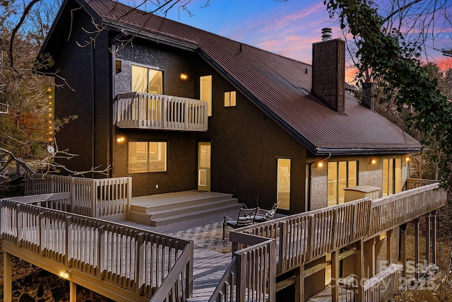 back house at dusk with a wooden deck