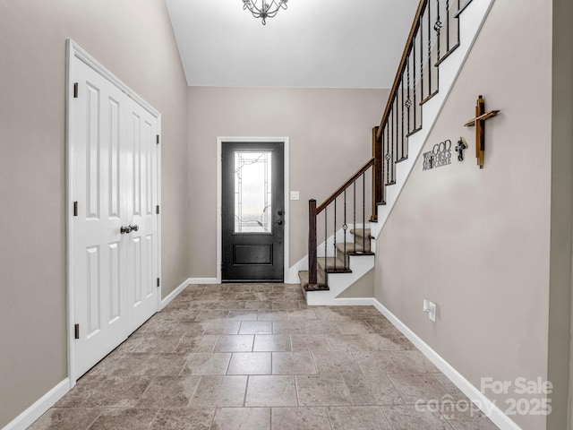 foyer featuring stone finish flooring, stairs, and baseboards