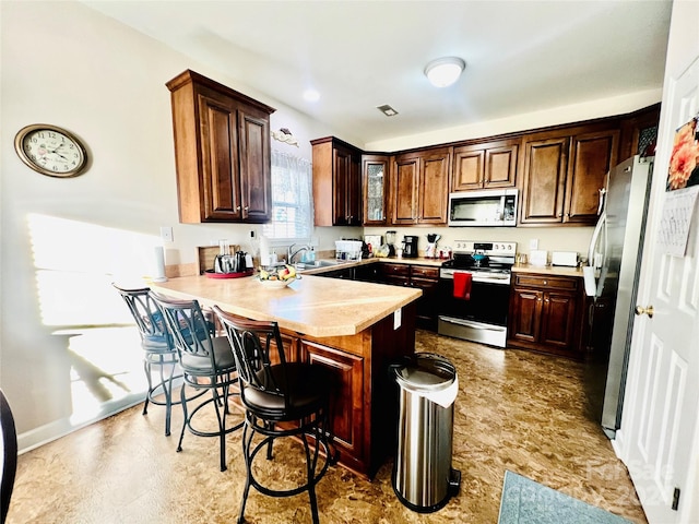 kitchen with kitchen peninsula, stainless steel appliances, a breakfast bar area, and sink