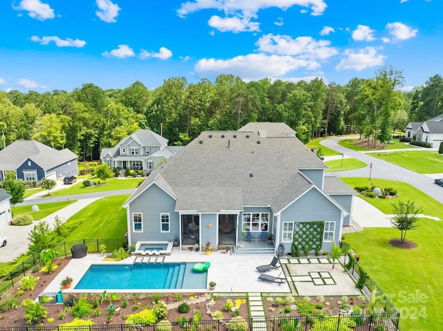 back of property with a patio area, a fenced in pool, and a yard