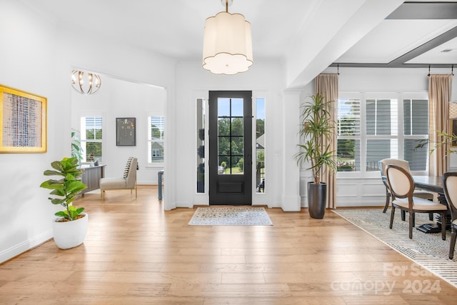 foyer entrance featuring crown molding, light hardwood / wood-style flooring, and an inviting chandelier