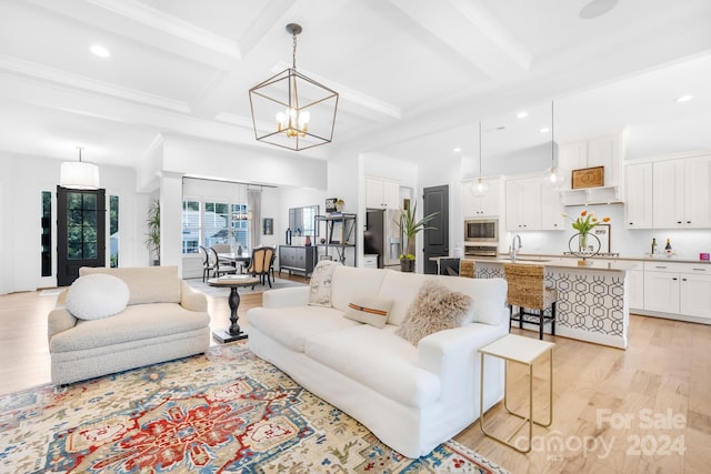 living room with beam ceiling, sink, coffered ceiling, an inviting chandelier, and light wood-type flooring