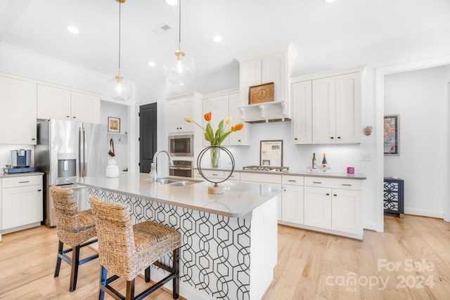 kitchen featuring sink, an island with sink, light hardwood / wood-style floors, a breakfast bar area, and stainless steel appliances