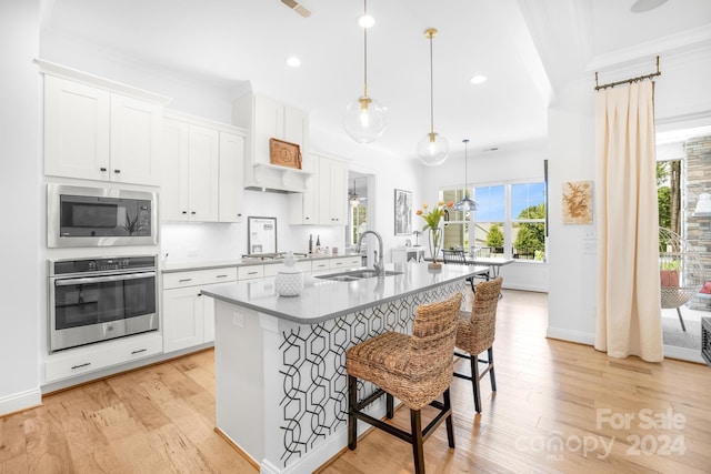 kitchen featuring sink, white cabinets, decorative light fixtures, and appliances with stainless steel finishes