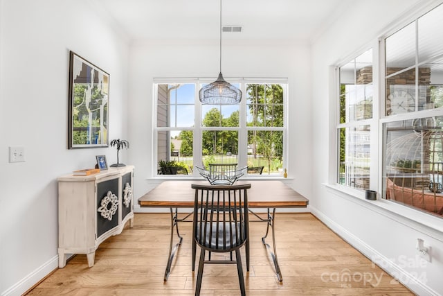 dining area with light hardwood / wood-style floors, plenty of natural light, and crown molding