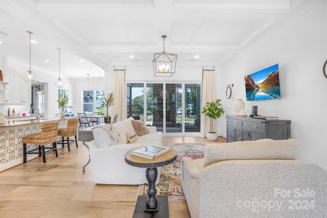 living room featuring ornamental molding, coffered ceiling, a chandelier, beamed ceiling, and light hardwood / wood-style floors