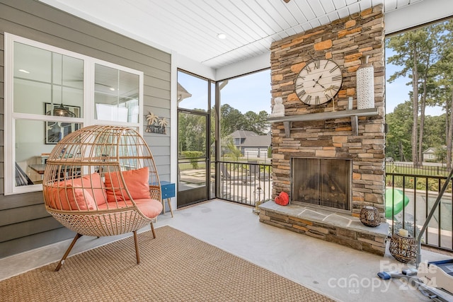 sunroom / solarium featuring a stone fireplace and wood ceiling