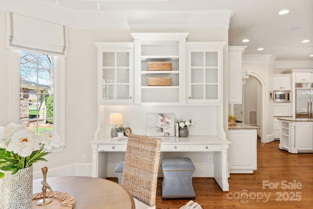 bar with arched walkways, crown molding, recessed lighting, wood finished floors, and built in appliances