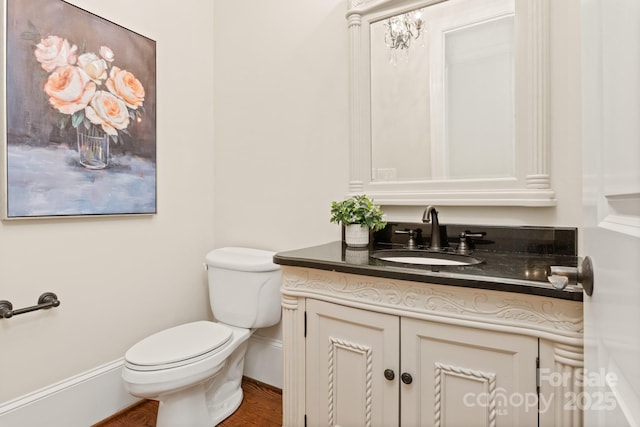 bathroom with toilet, baseboards, and vanity