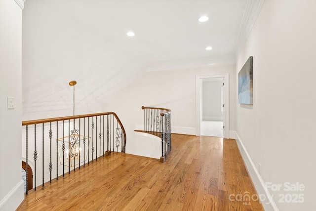 hallway featuring baseboards, wood finished floors, crown molding, an upstairs landing, and recessed lighting