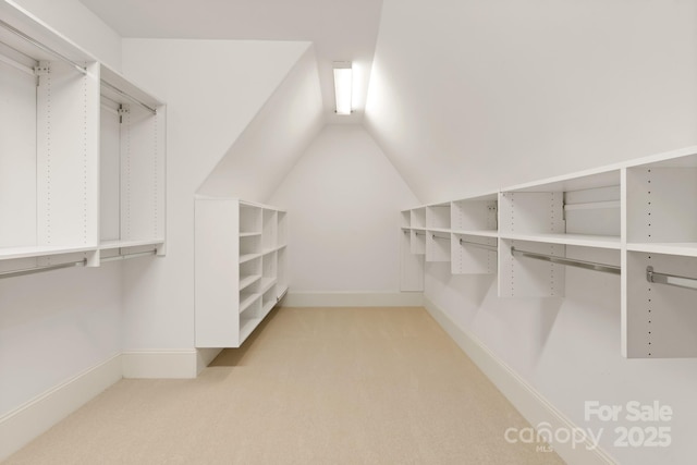 walk in closet featuring light carpet and vaulted ceiling