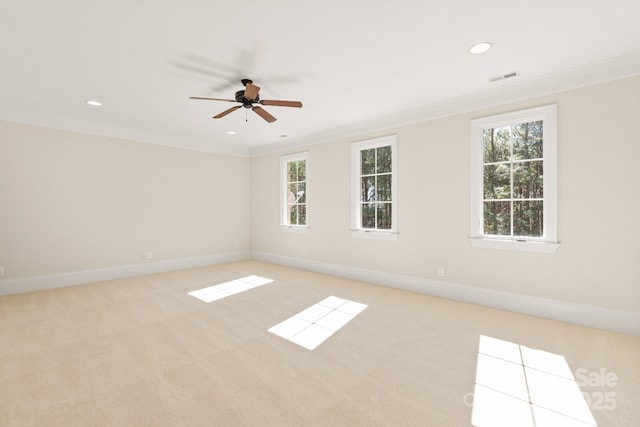 spare room featuring light colored carpet, a healthy amount of sunlight, crown molding, and visible vents