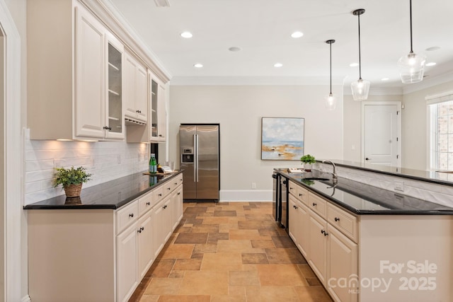 kitchen with a sink, ornamental molding, stainless steel fridge, and decorative backsplash