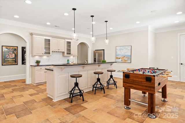 kitchen featuring dark countertops, a breakfast bar, arched walkways, and stainless steel refrigerator with ice dispenser