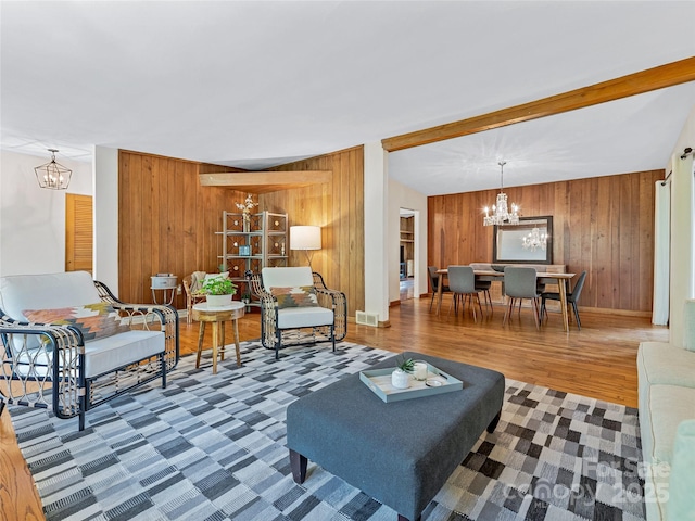 living room with wood-type flooring, lofted ceiling with beams, wood walls, and an inviting chandelier