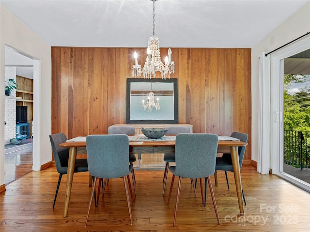 dining space featuring wood-type flooring, a notable chandelier, and wooden walls