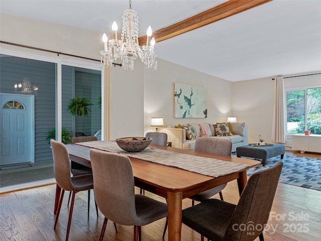 dining space featuring beamed ceiling, a chandelier, and light hardwood / wood-style flooring