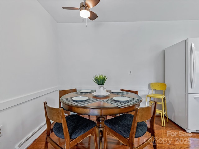 dining space featuring a baseboard heating unit, ceiling fan, and light wood-type flooring