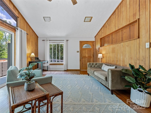 living room featuring hardwood / wood-style floors, vaulted ceiling, a textured ceiling, and wooden walls