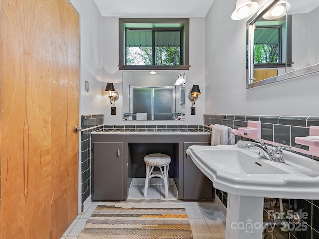 bathroom with tile patterned flooring, tile walls, and sink