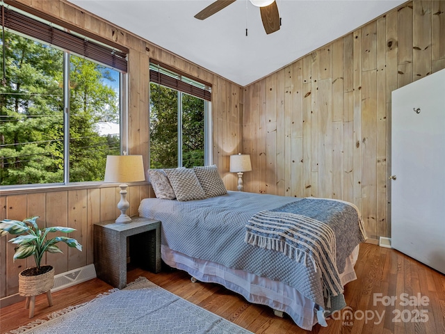 bedroom featuring wood walls, ceiling fan, and hardwood / wood-style flooring