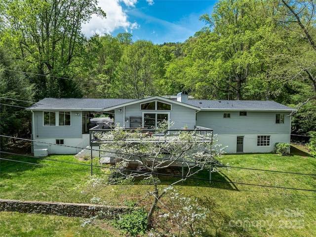 back of house with a deck and a lawn