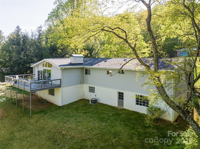 rear view of house featuring a wooden deck, central AC unit, and a lawn