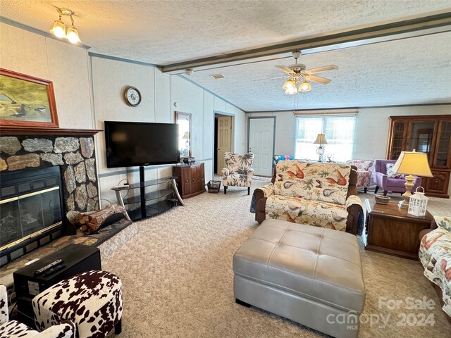 carpeted living room featuring vaulted ceiling with beams, ceiling fan, a stone fireplace, and a textured ceiling