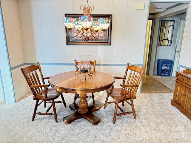 dining area featuring a notable chandelier and light carpet