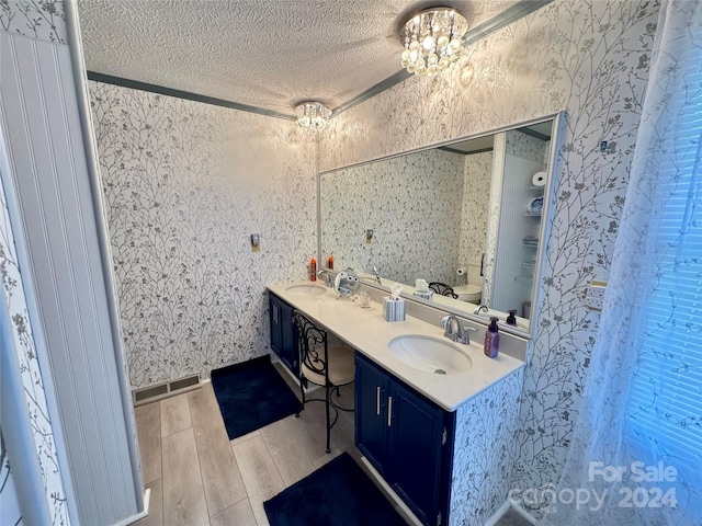 bathroom with hardwood / wood-style flooring, a notable chandelier, a textured ceiling, and vanity