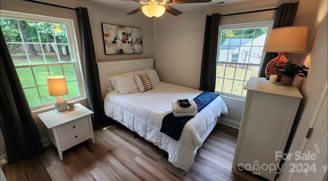 bedroom with hardwood / wood-style floors, ceiling fan, and multiple windows