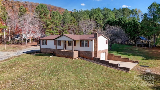 view of front of house with covered porch, a front yard, and a garage