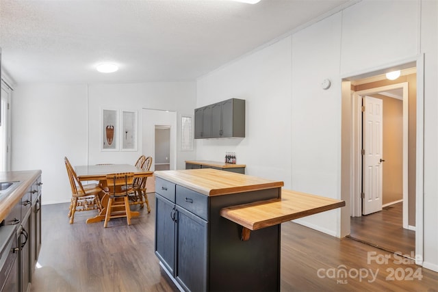 kitchen with dark hardwood / wood-style flooring, a textured ceiling, butcher block counters, a center island, and lofted ceiling