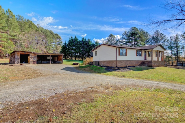 view of side of property with a yard, a carport, and an outdoor structure