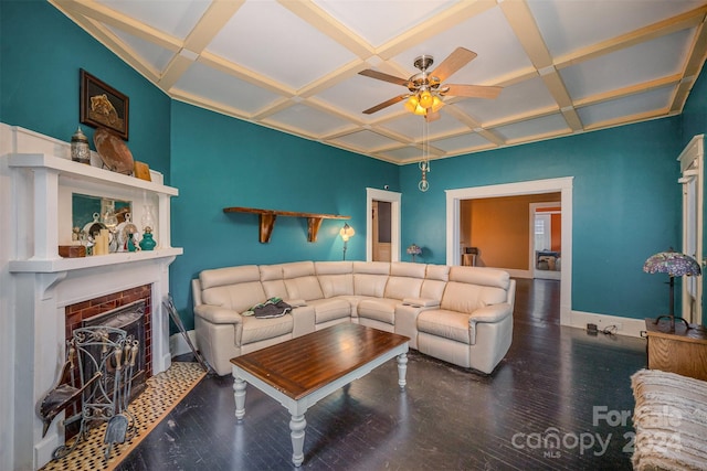 living room with ceiling fan, coffered ceiling, dark hardwood / wood-style flooring, beamed ceiling, and a fireplace