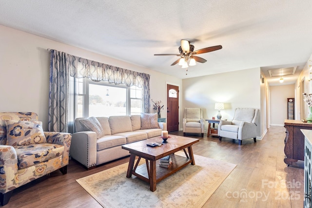 living room with ceiling fan, hardwood / wood-style flooring, and a textured ceiling