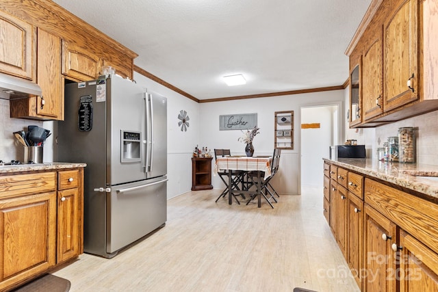 kitchen featuring crown molding, decorative backsplash, stainless steel fridge, and light stone countertops